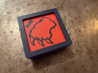 Red square with bear design and 'BEAR' text on a textured surface