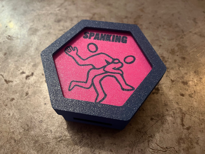 Hexagonal object with pink center and black design on a textured surface